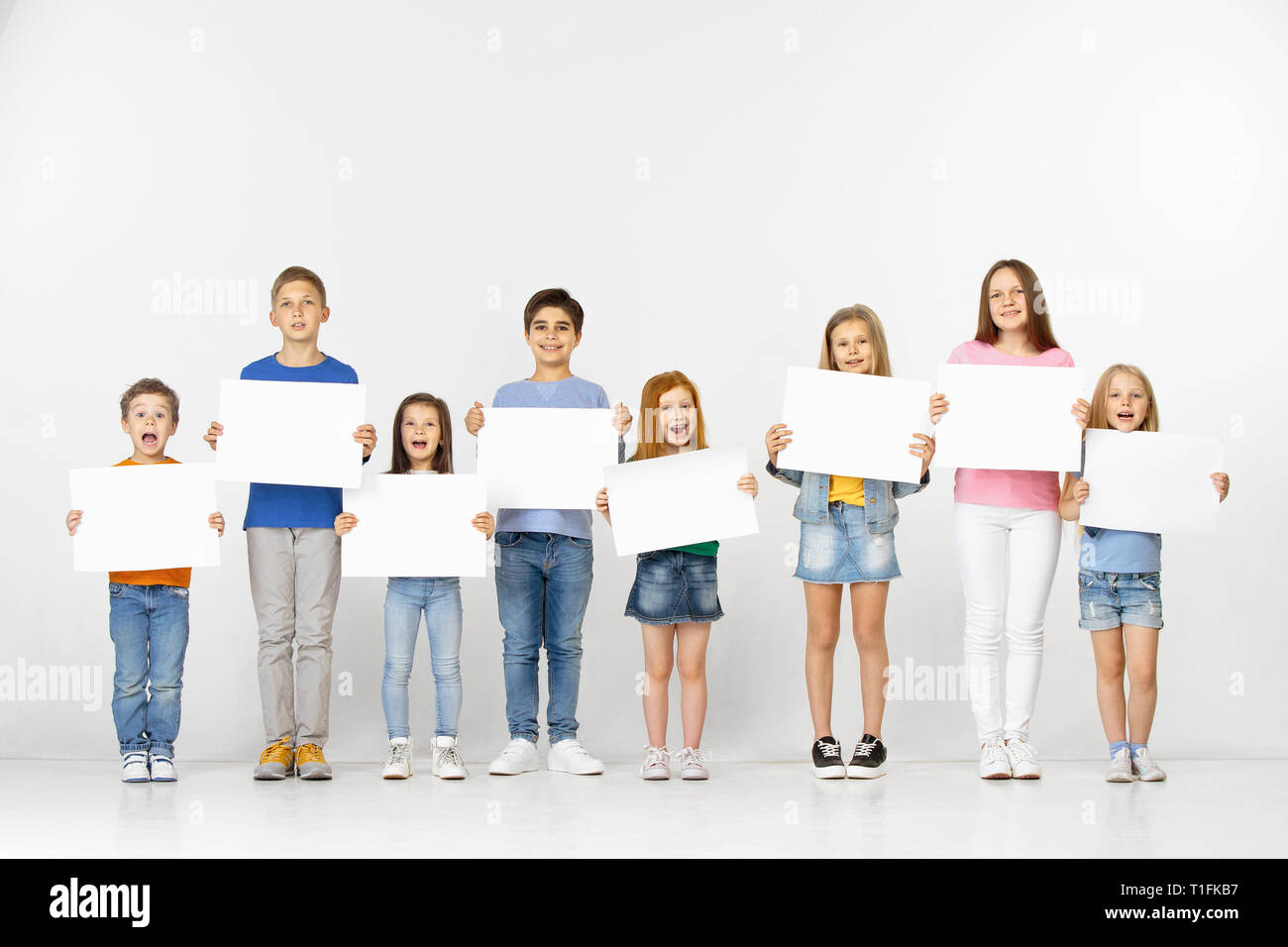 Group of happy smiling children with a white empty banners isolated in ...