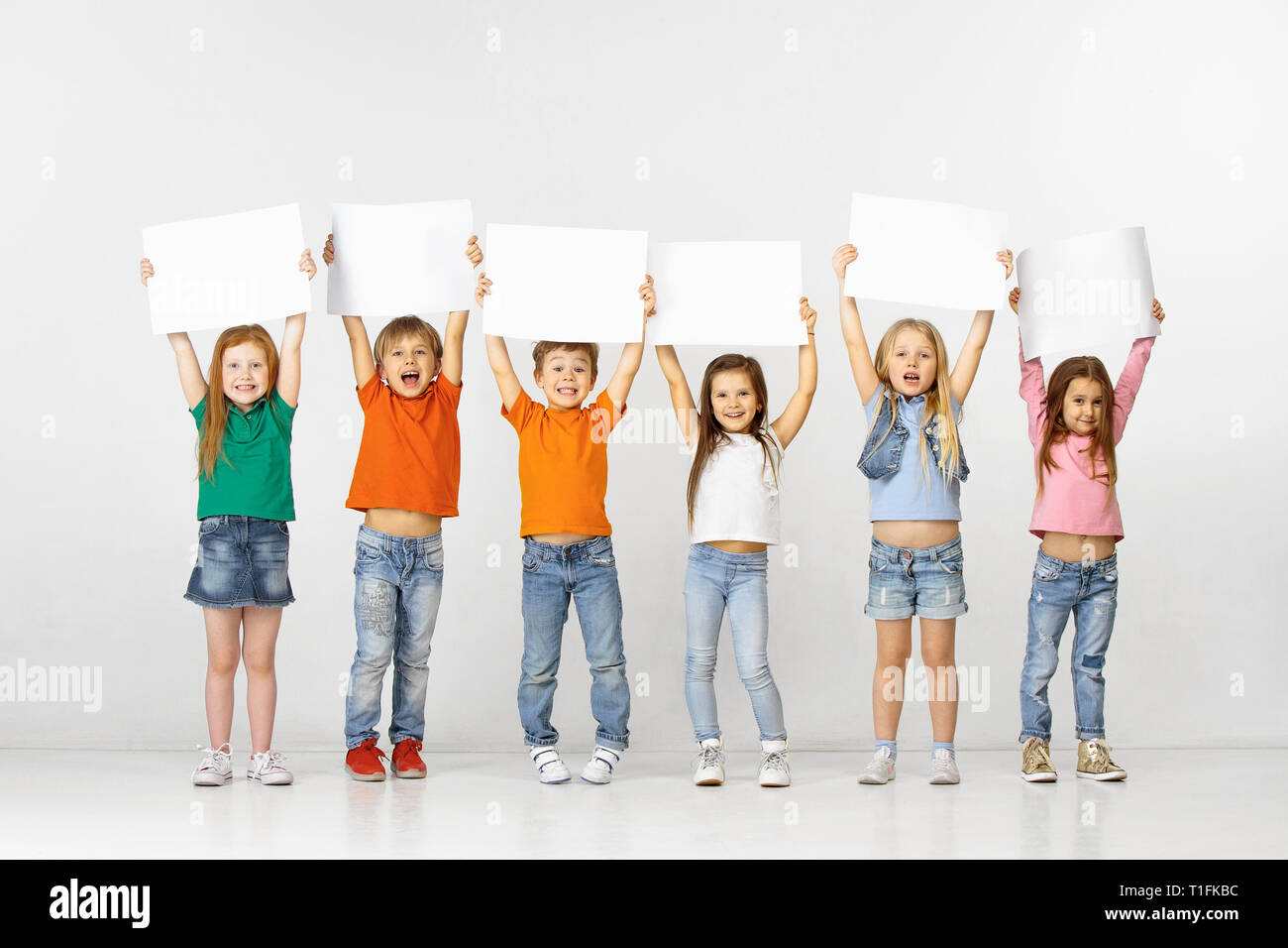Group of happy smiling children with a white empty banners isolated in ...