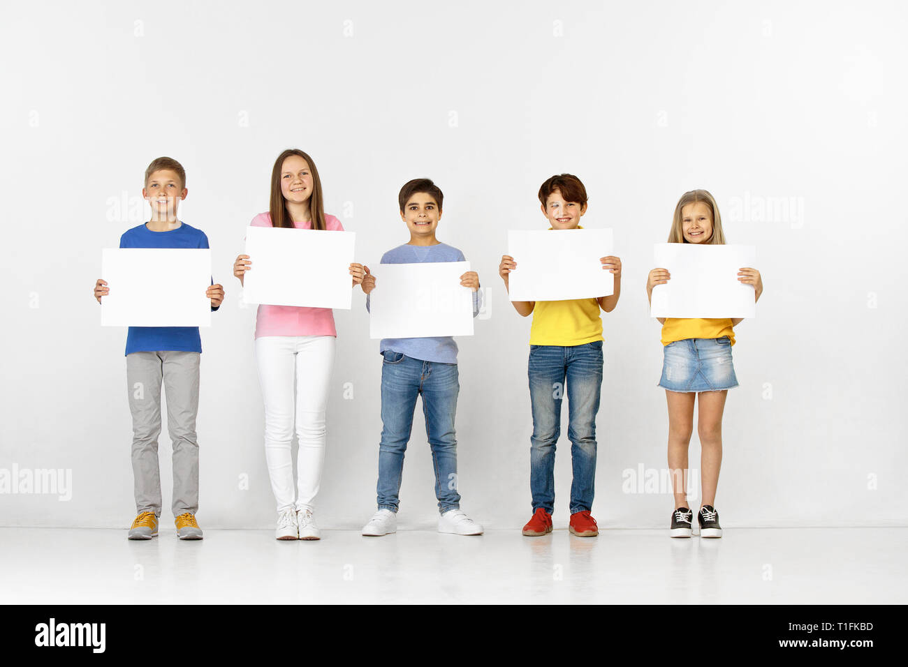 Group of happy smiling children with a white empty banners isolated in ...