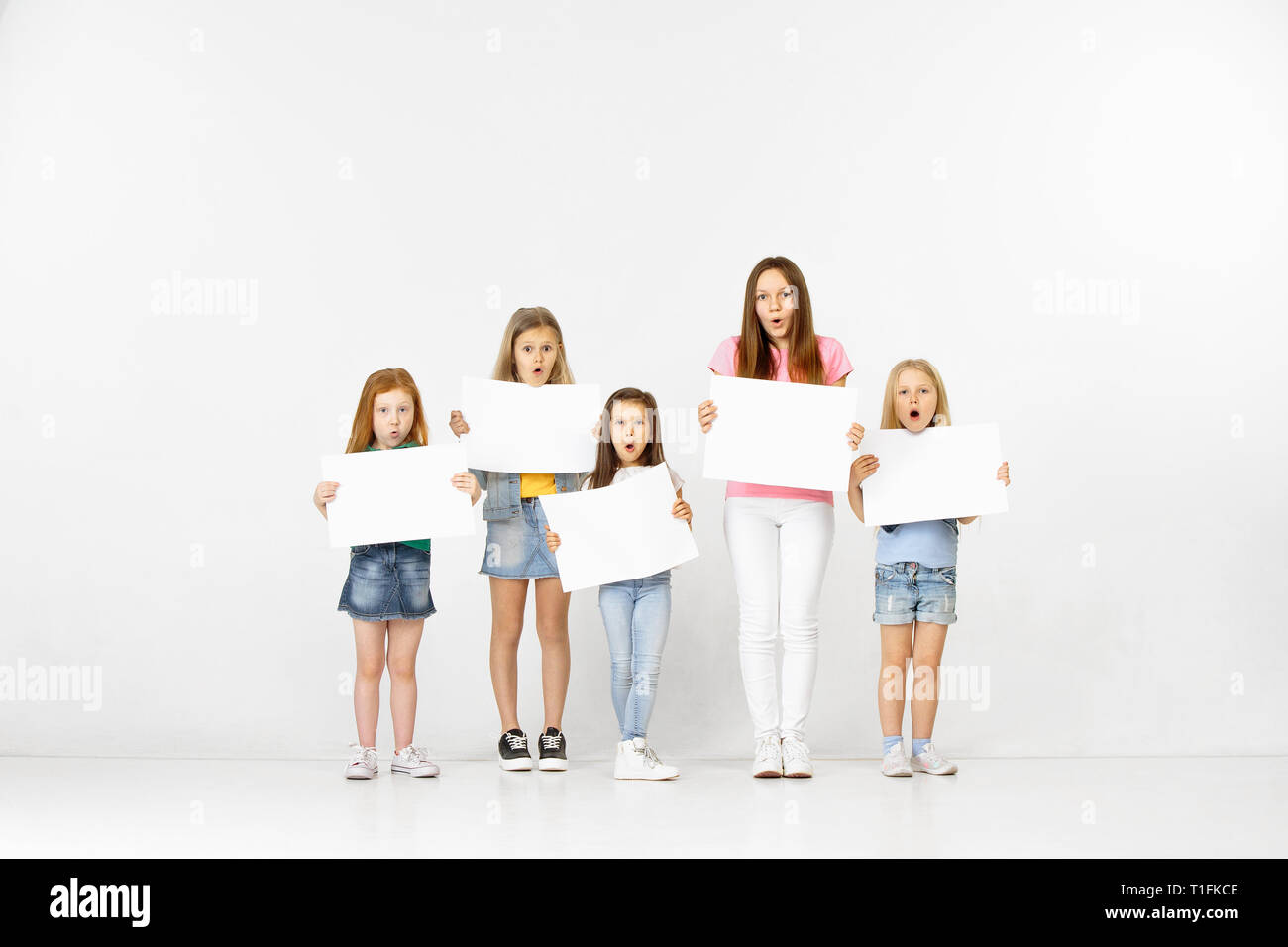 Group of happy surprised children with a white empty banners isolated ...