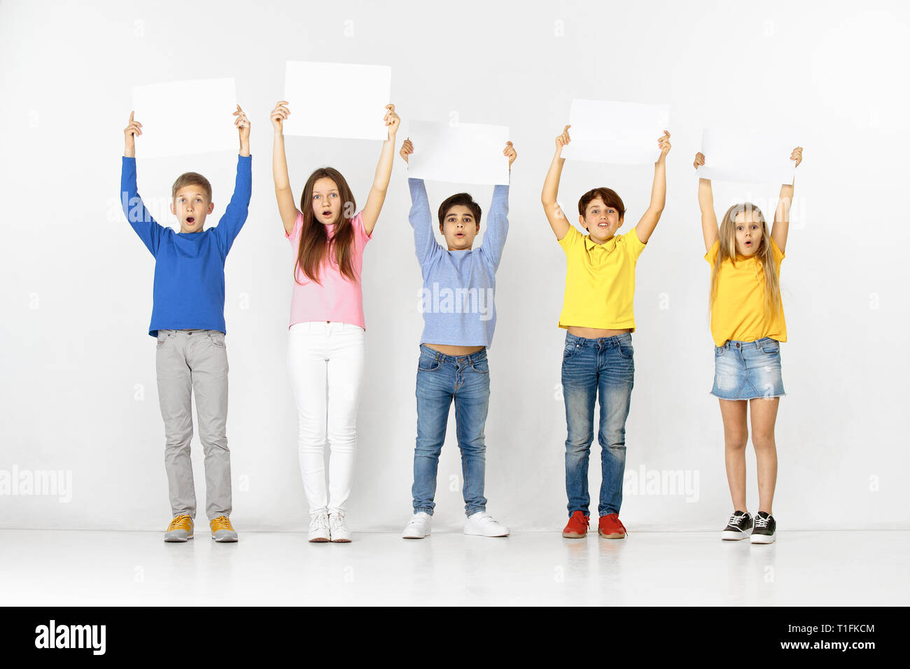 Group of happy surprised children with a white empty banners isolated ...