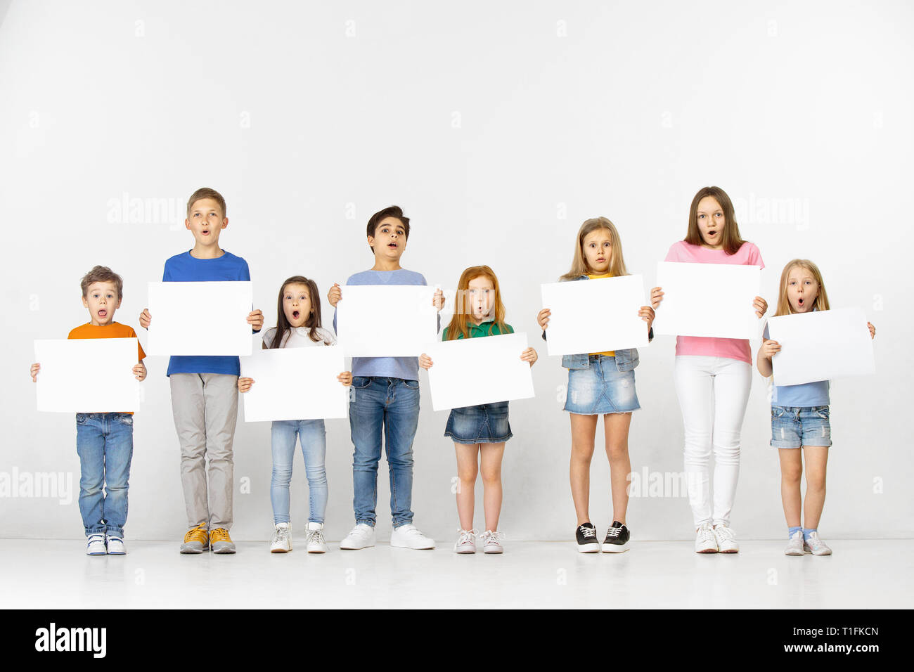Group of happy surprised children with a white empty banners isolated ...