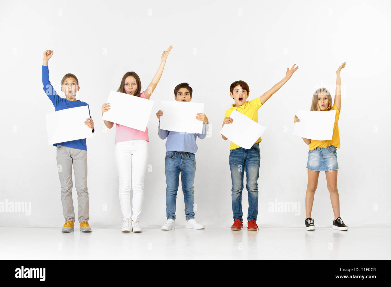 Group of happy surprised children with a white empty banners isolated ...