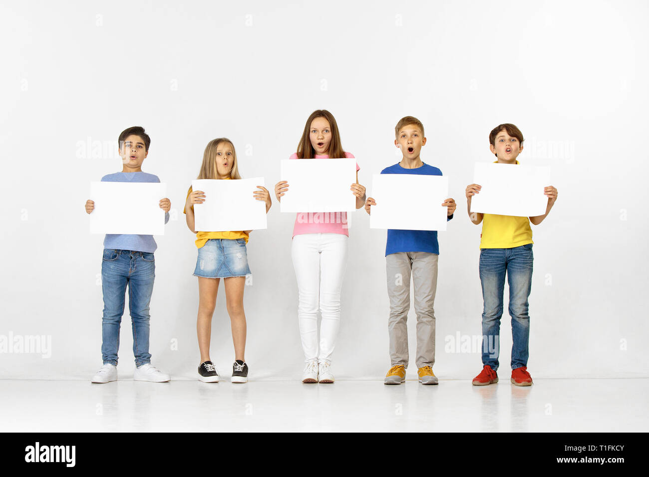 Group of happy surprised children with a white empty banners isolated ...