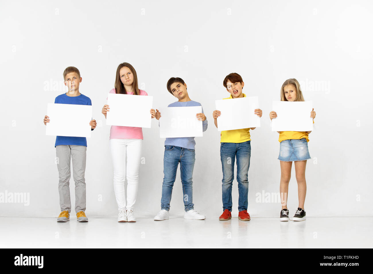 Group Of Sad Serious Children With A White Empty Banners Isolated