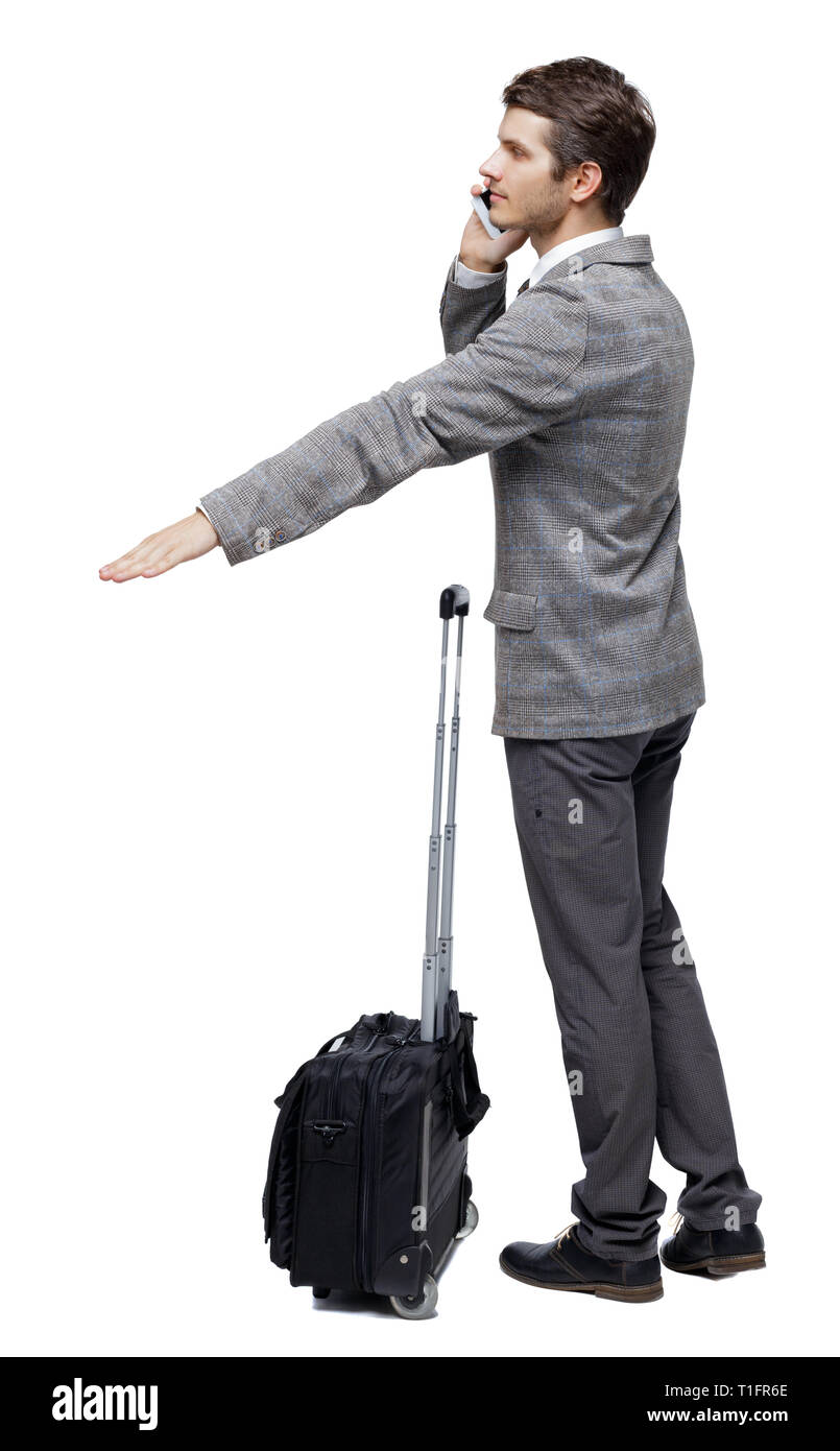 Back view of pointing business man with suitcase talking on the phone ...