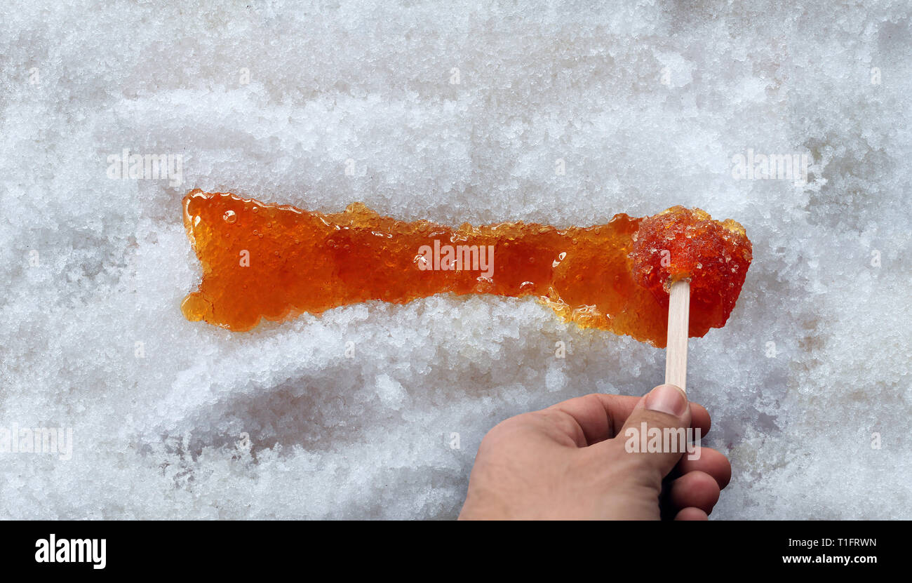 Maple taffy or boiled tree sweet boiled sap syrup on snow as a traditional spring food culture from Quebec Ontario Canada and New England. Stock Photo