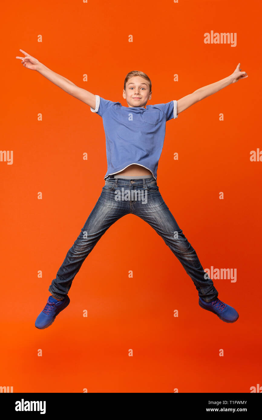 Happy boy jumping on orange studio background Stock Photo