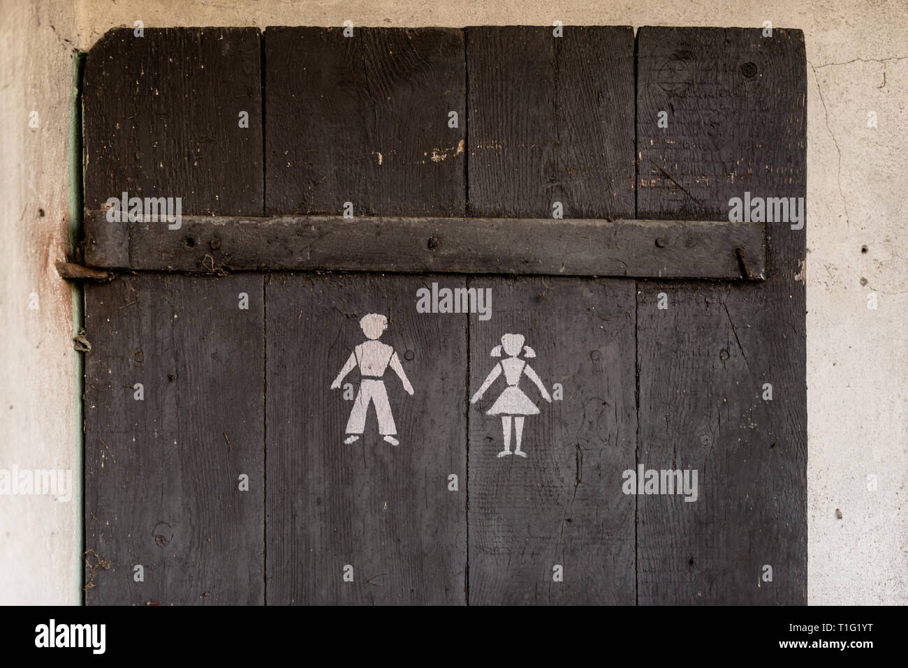 A door from an old outhouse standing outside with a symbol of a man and a woman. Stock Photo