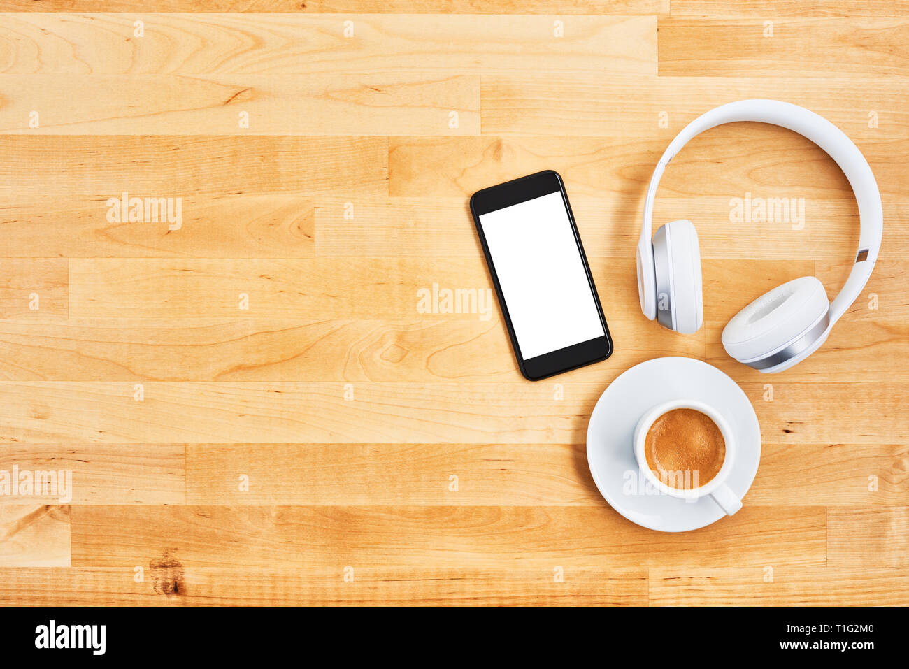 Smartphone with blank white screen, wireless headphone and cup of coffee on wooden office desk. Top view. Copy space for text or design. Flat lay. Stock Photo