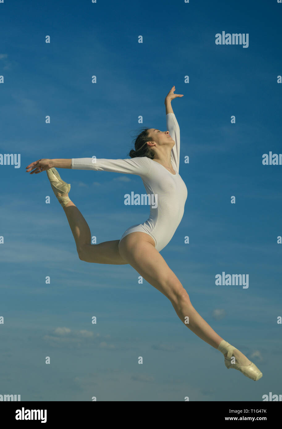 Grace and beauty. Classic dance style. Young ballerina jumping on blue sky. Cute ballet dancer. Pretty woman in dance wear. Practicing art of Stock Photo