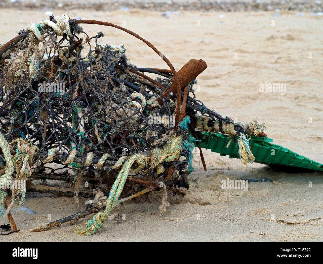 The battered remains of a crab or lobster pot on a Norfolk beach poses a danger to marine life (seals and fish) from plastics and netting Stock Photo