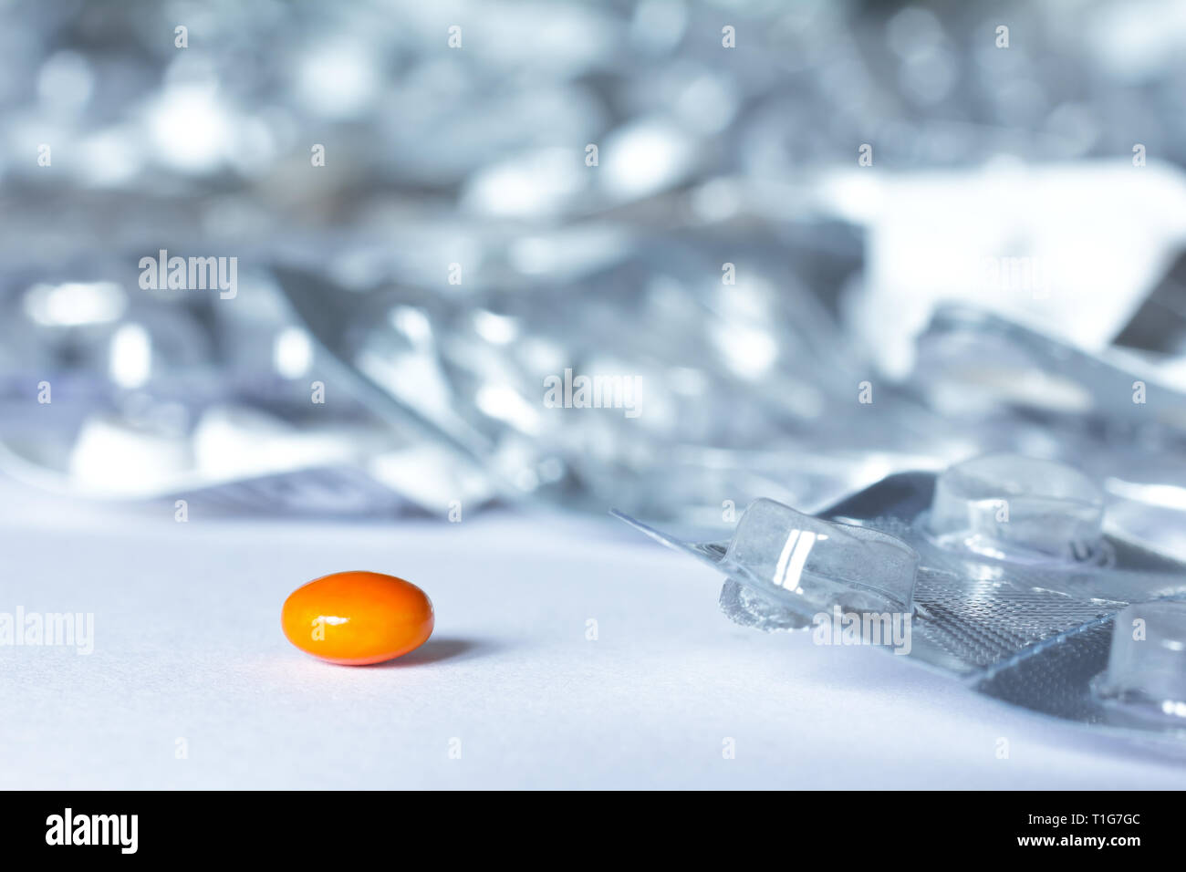 One single pill in front of many empty blister packages on white background, drug misuse concept Stock Photo