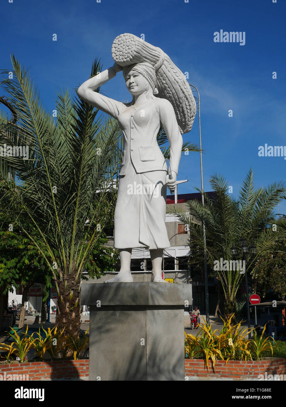 Battambang, Cambodia. The Rice Harvest statue depicts a woman in a skirt with a sheaf of rice balanced on her head and a sickle in her hand. Stock Photo