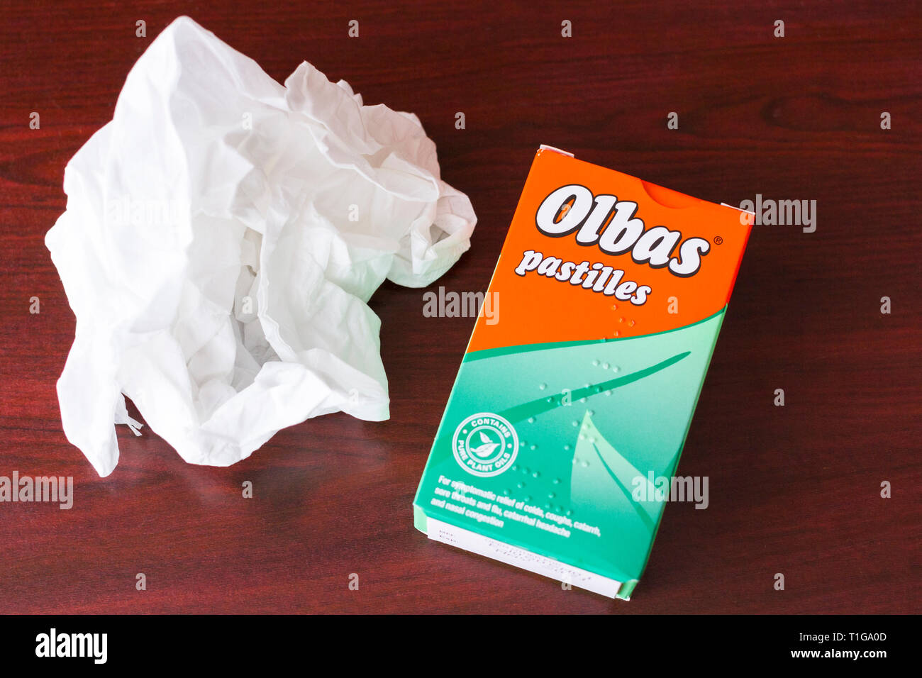 Box of Olbas pastilles for sore throats, coughs, colds and nasal congestion. with a used tissue. United Kingdom Stock Photo