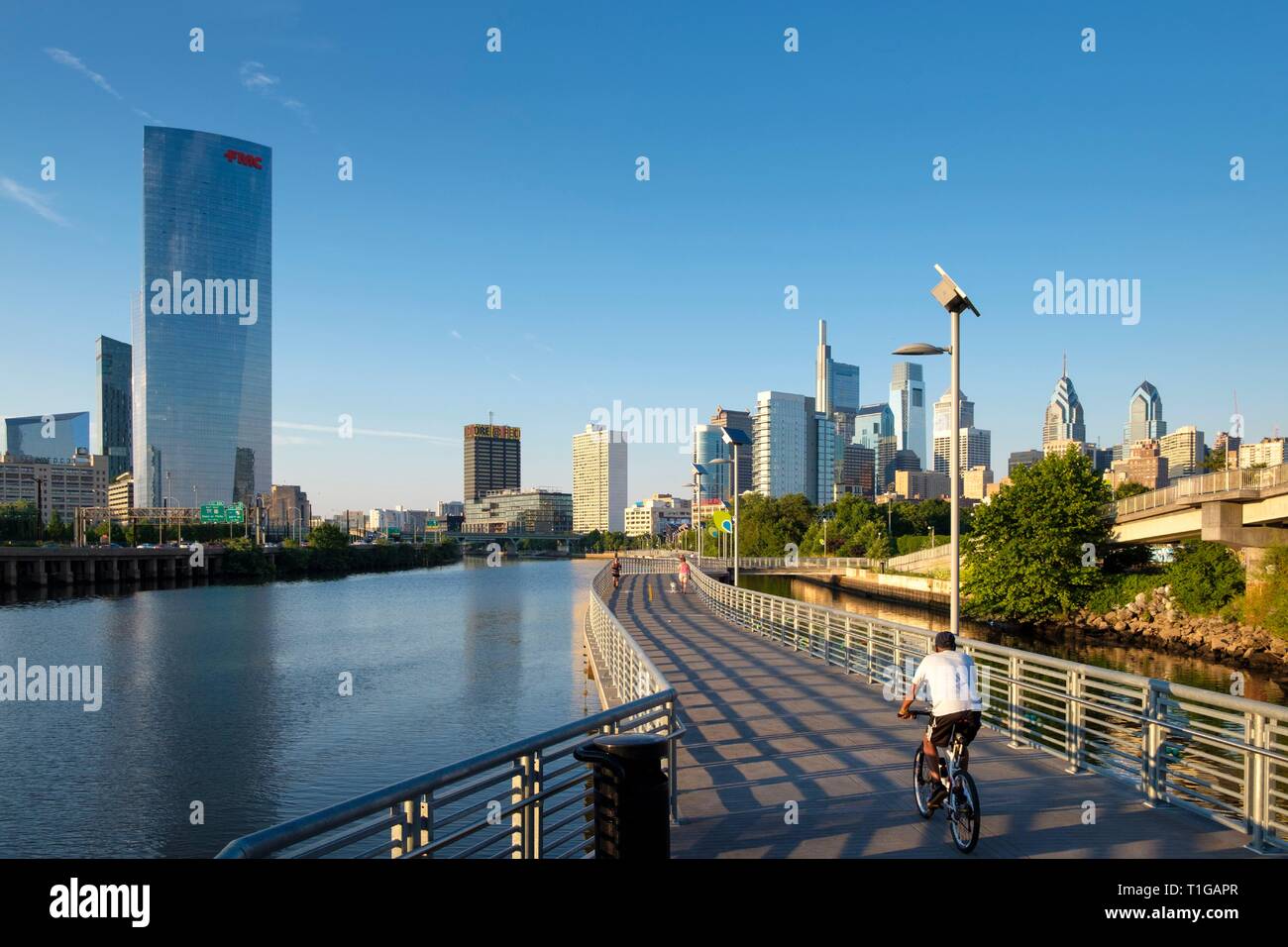 Philadelphia Skyline and Schuylkill River Park Boardwalk with Cyclist at sunset, Philadelphia, Pennsylvania. Stock Photo