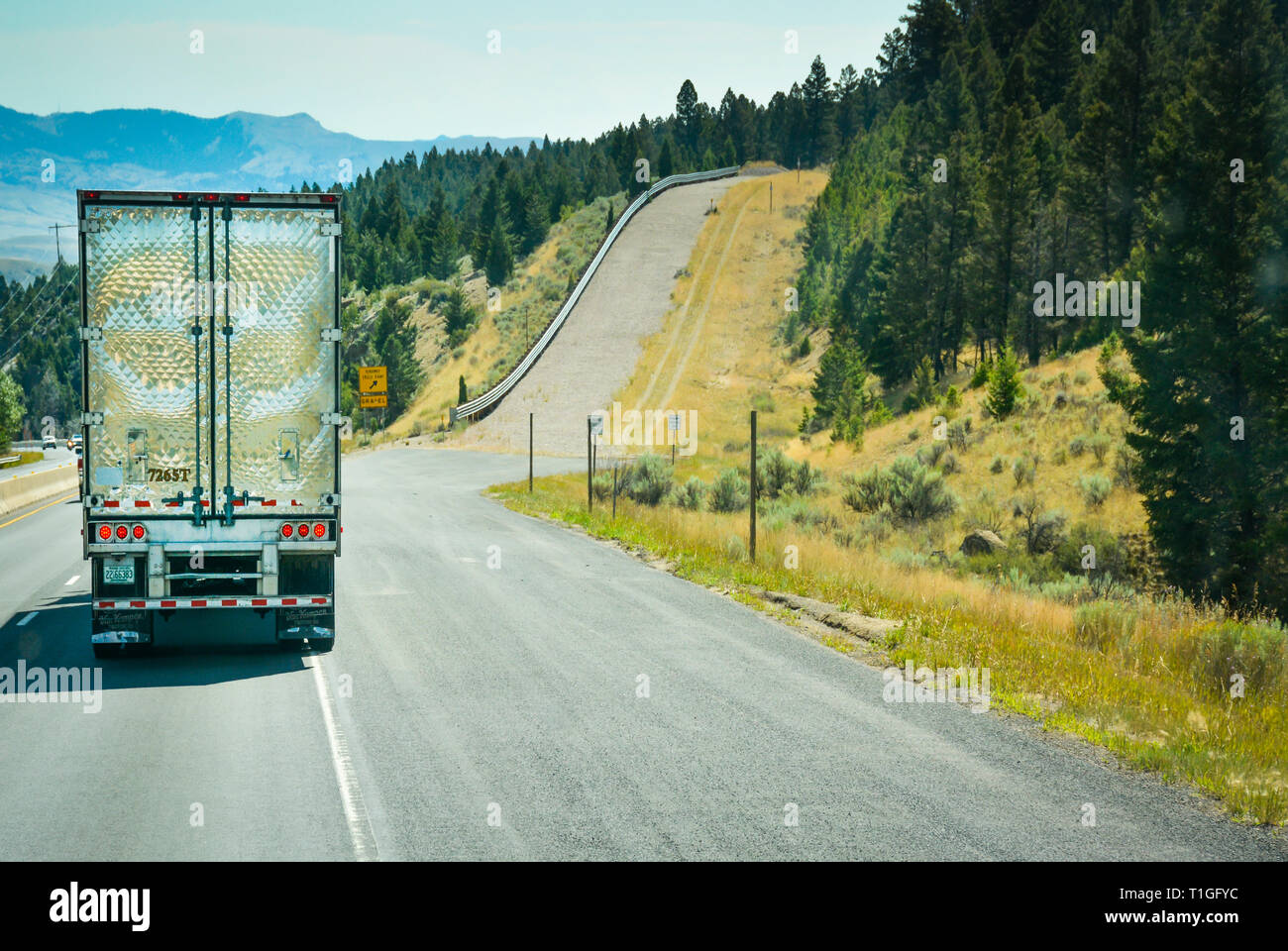 A big rig truck heads downhill alongside an empty runaway truck ramp up a steep slope off of the interstate I-90 highway in Montana, USA Stock Photo