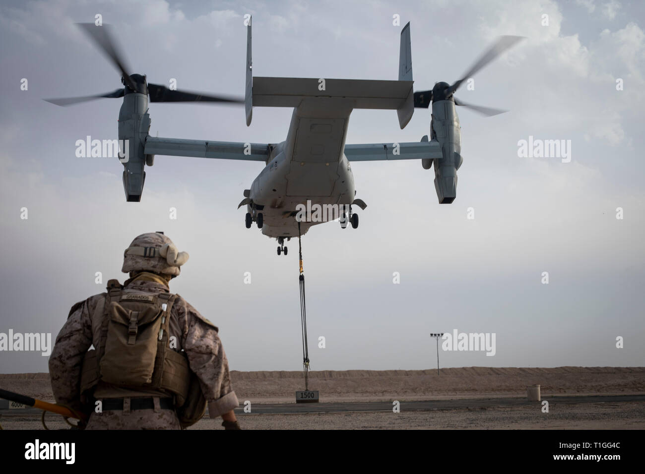 U.S. Marine Corps Cpl. Michael Granados, a landing support specialist with Combat Logistics Detachment 34, attached Special Purpose Marine Air Ground Task Force Crisis Response-Central Command, watches as an MV-22 Osprey carries a 1,500-pound load during a Helicopter Support Team exercise in support of Marine Medium Tiltrotor Squadron 264, also attached to SPMAGTF-CR-CC, in Southwest Asia, March 20, 2019. The HST exercise provides proficiency training to landing support specialists with CLD 34 and VMM-264 pilots in the insertion and extraction of assets in restrictive terrain. (U.S. Marine Cor Stock Photo
