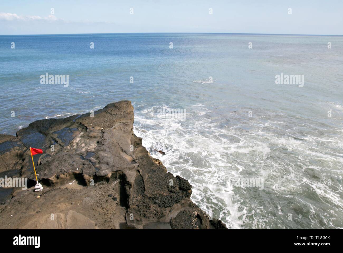 Red flag on the rocks by the sea side Stock Photo - Alamy