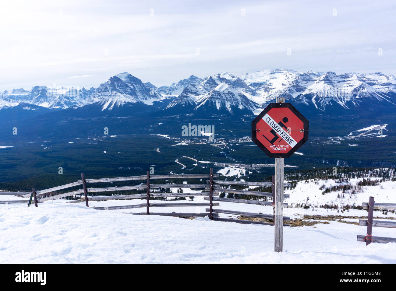 An avalanche danger warning sign prevents skiers from venturing into dangerous territory with the picturesque Canadian Rockies of Alberta in the backg Stock Photo