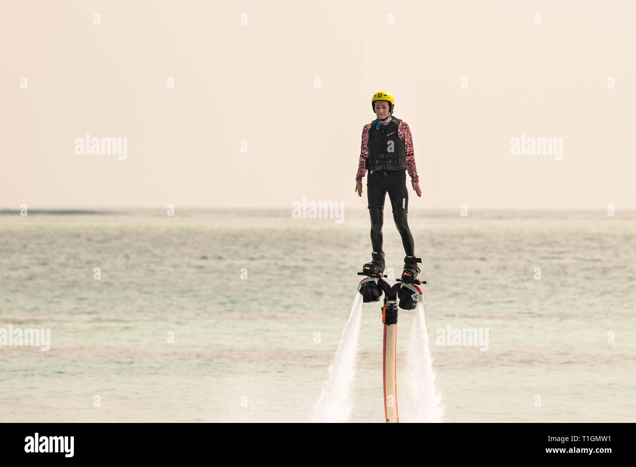 Rangali, Maldives - February 14th, 2019: A woman suspended in the air using a water jet pack in Maldives. Stock Photo