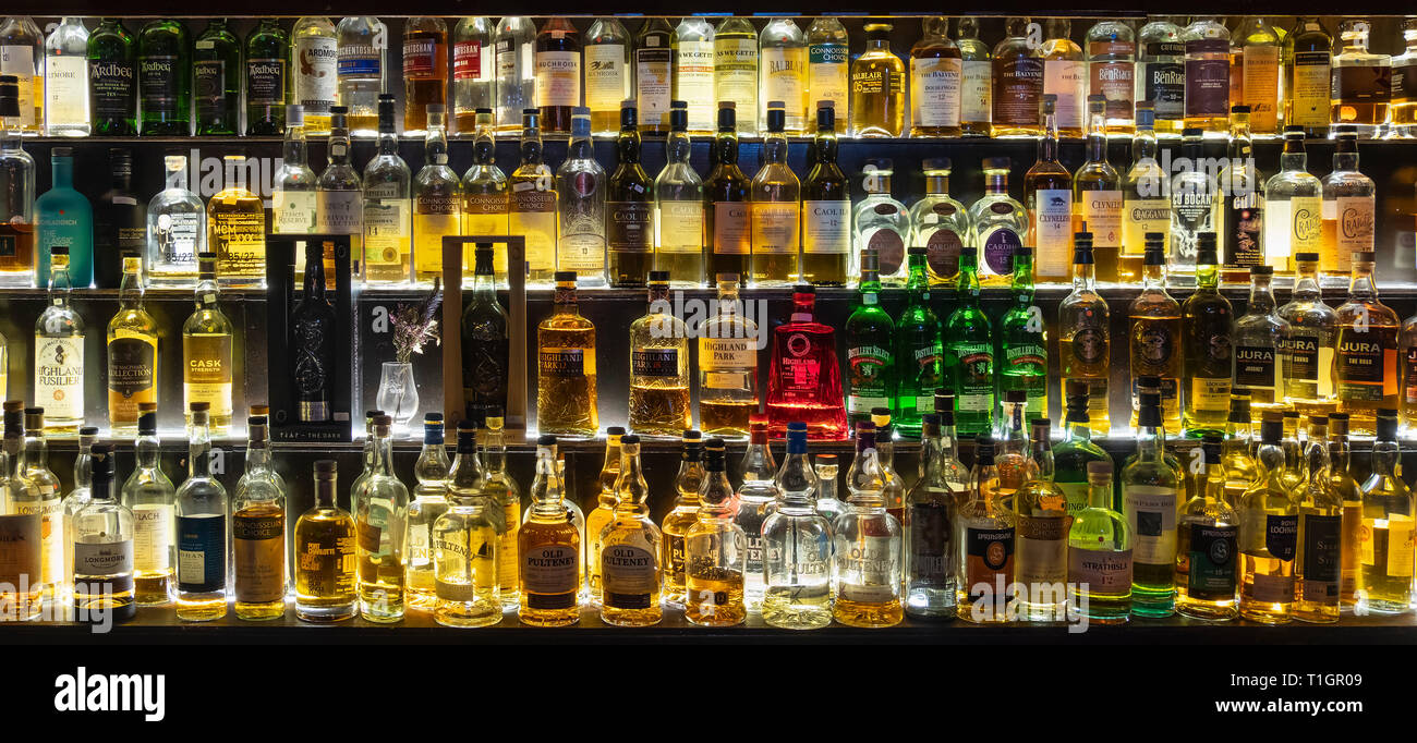 A large selection of Scottish Whiskies illuminated on glass shelves and in optics, Scotland Stock Photo