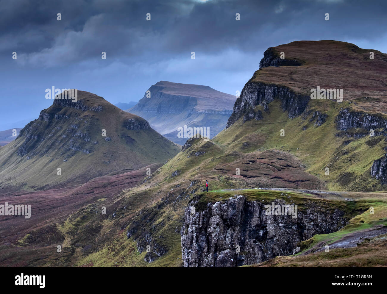 Man standing on the edge of the Quiraing at dawn, Trotternish Peninsula, Isle of Skye, Inner Hebrides, Scotland, UK. MODEL RELEASED Stock Photo