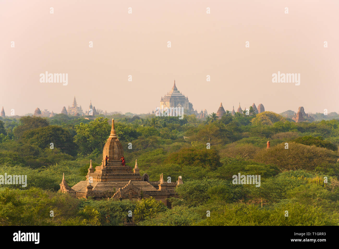 A unidentified Burmese couple, wearing a traditional Longyi, are taking photos and selfies from the roof of one of many temples in Bagan. Stock Photo