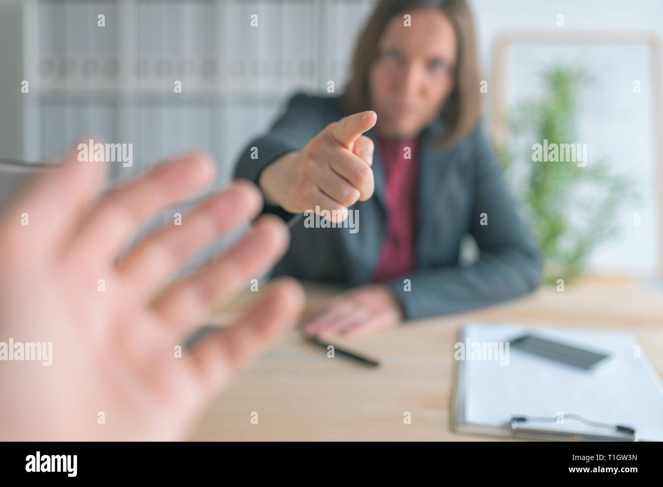 Boss threatening employee with finger in business office, conceptual image with selective focus Stock Photo