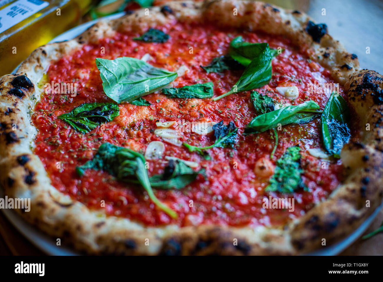 traditional authentic vegan neapolitan style wood fired pizza on table in a pizzeria trattoria restaurant. Close up. Vegan marinara. Plant based Stock Photo