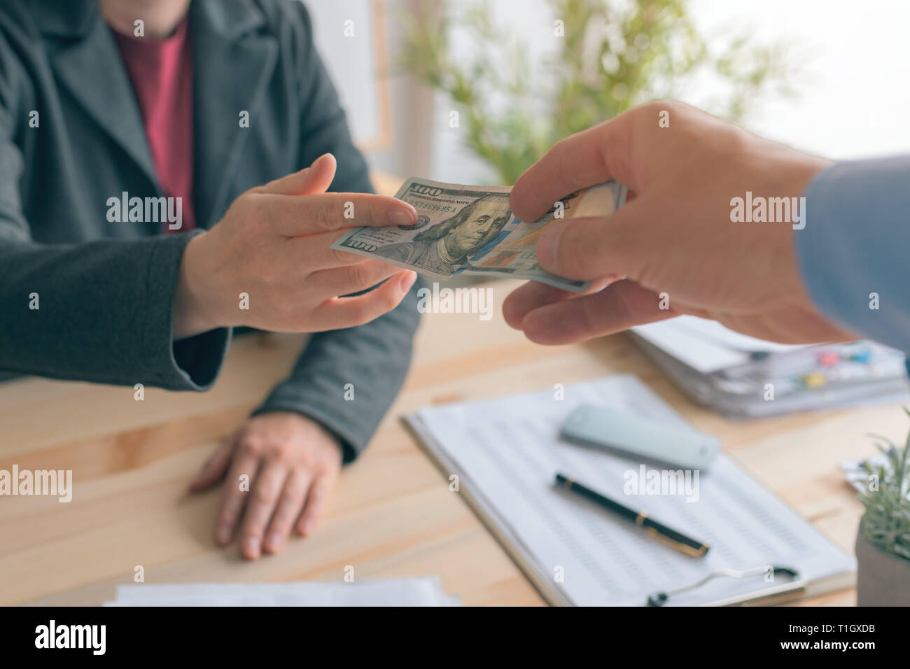 Hush money, bribe and corruption, man offering cash a 100 US dollar paper currency bill to female business person Stock Photo