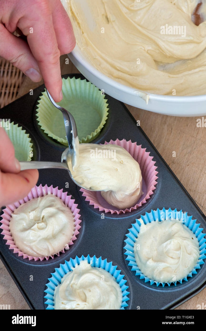 Spooning Vanilla cupcake mixture into cupcake cases. UK Stock Photo