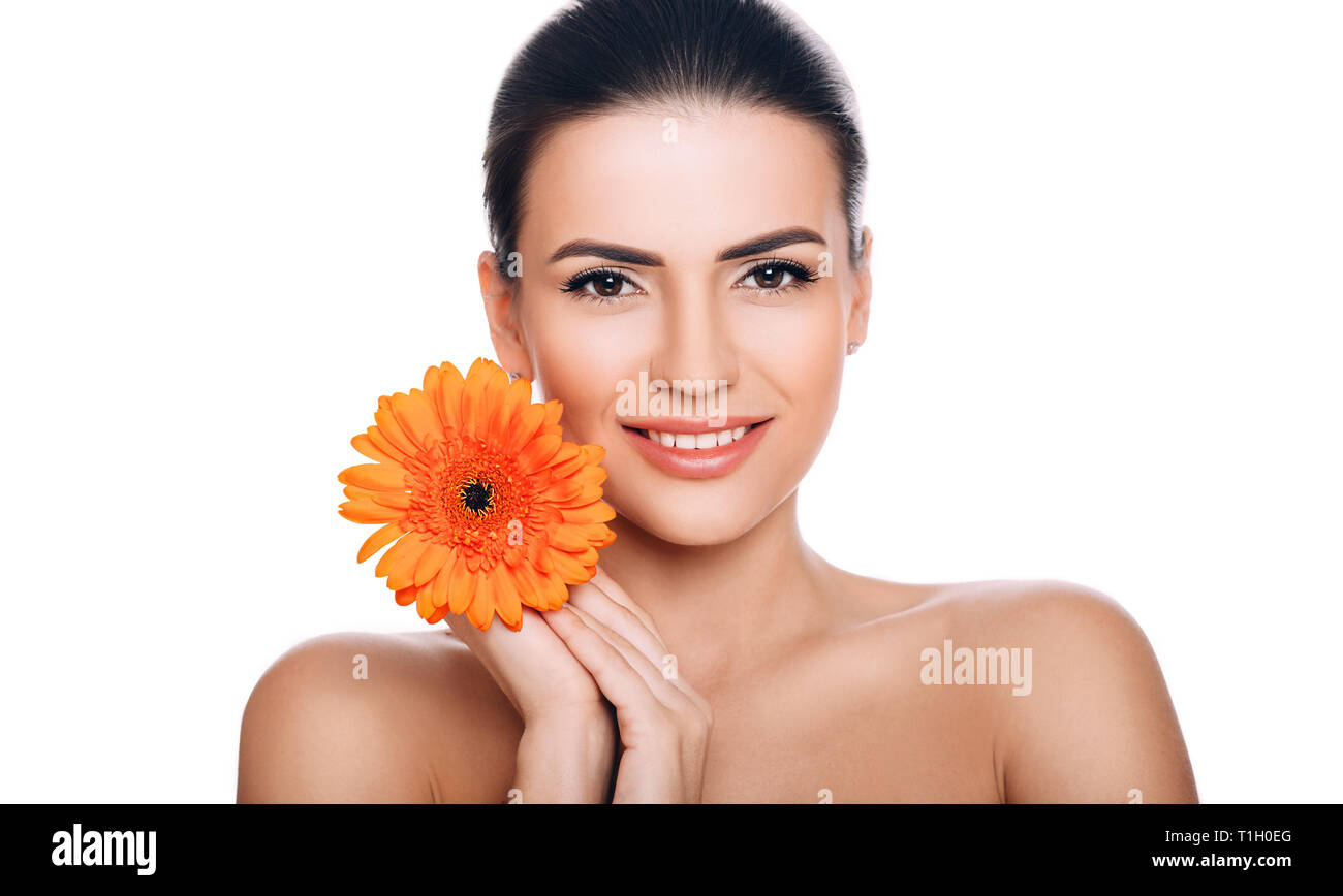 Beauty portrait of smiling woman with fresh shiny skin. Perfect face with gerbera Stock Photo