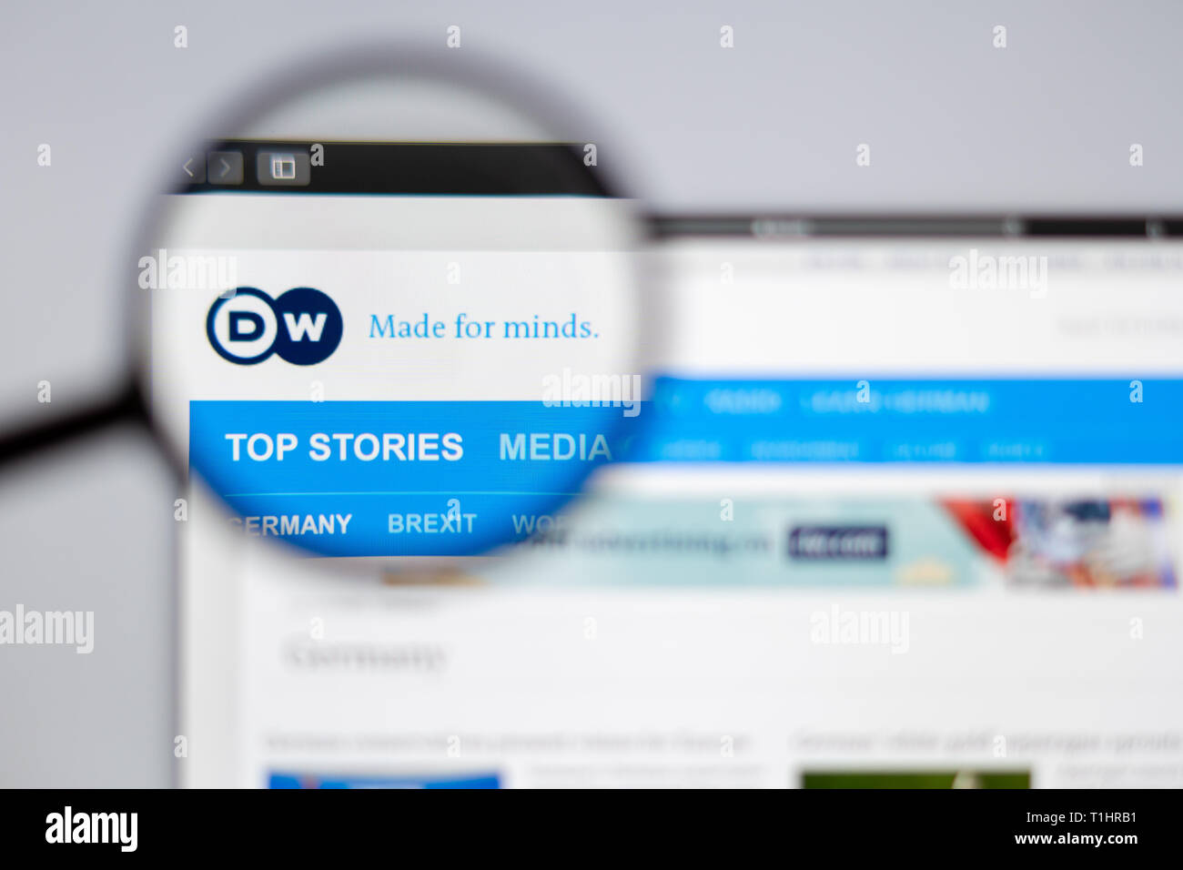 Germany news media Deutsche Welle website homepage. DW logo visible  through a magnifying glass. Stock Photo