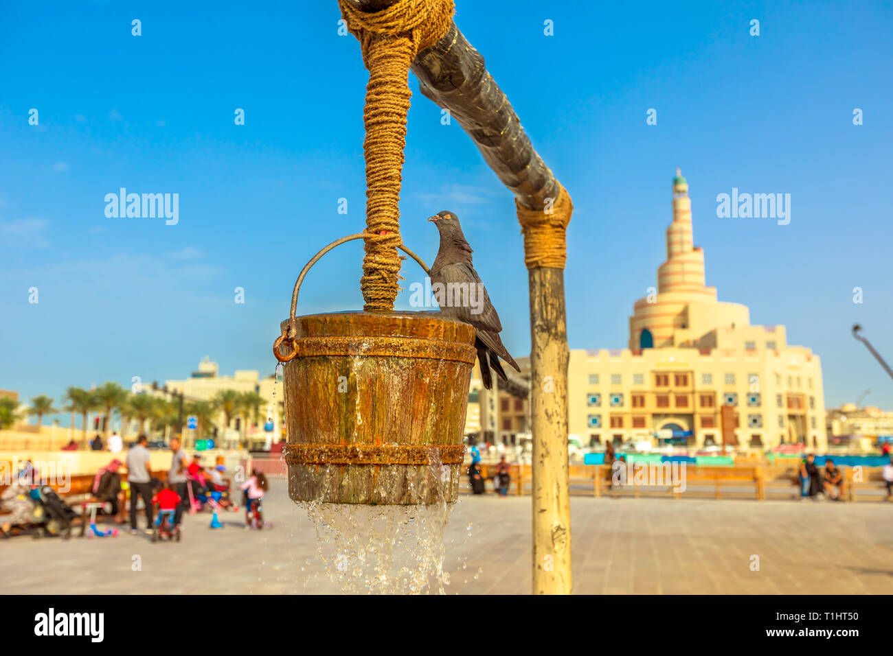 Pigeon at old well fountain on foreground at blue sky, iconic landmark in the middle of Souq Waqif, Doha center, Qatar. Middle East, Arabian Peninsula Stock Photo