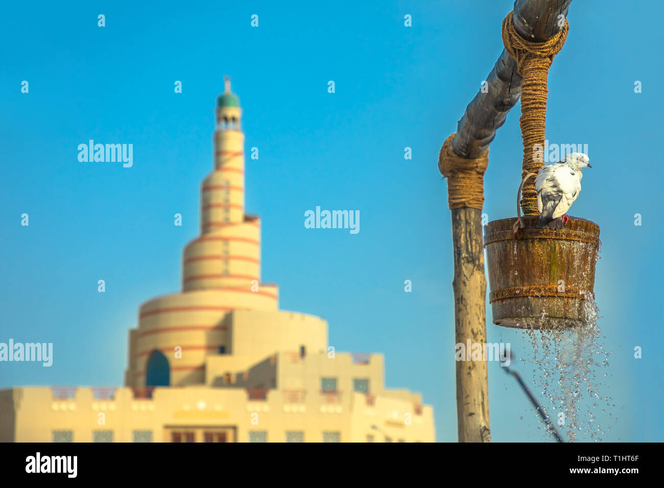 Pigeon drinks water at old well fountain, iconic landmark in the middle of Souq Waqif in Doha city center, Qatar. Middle East, Arabian Peninsula Stock Photo