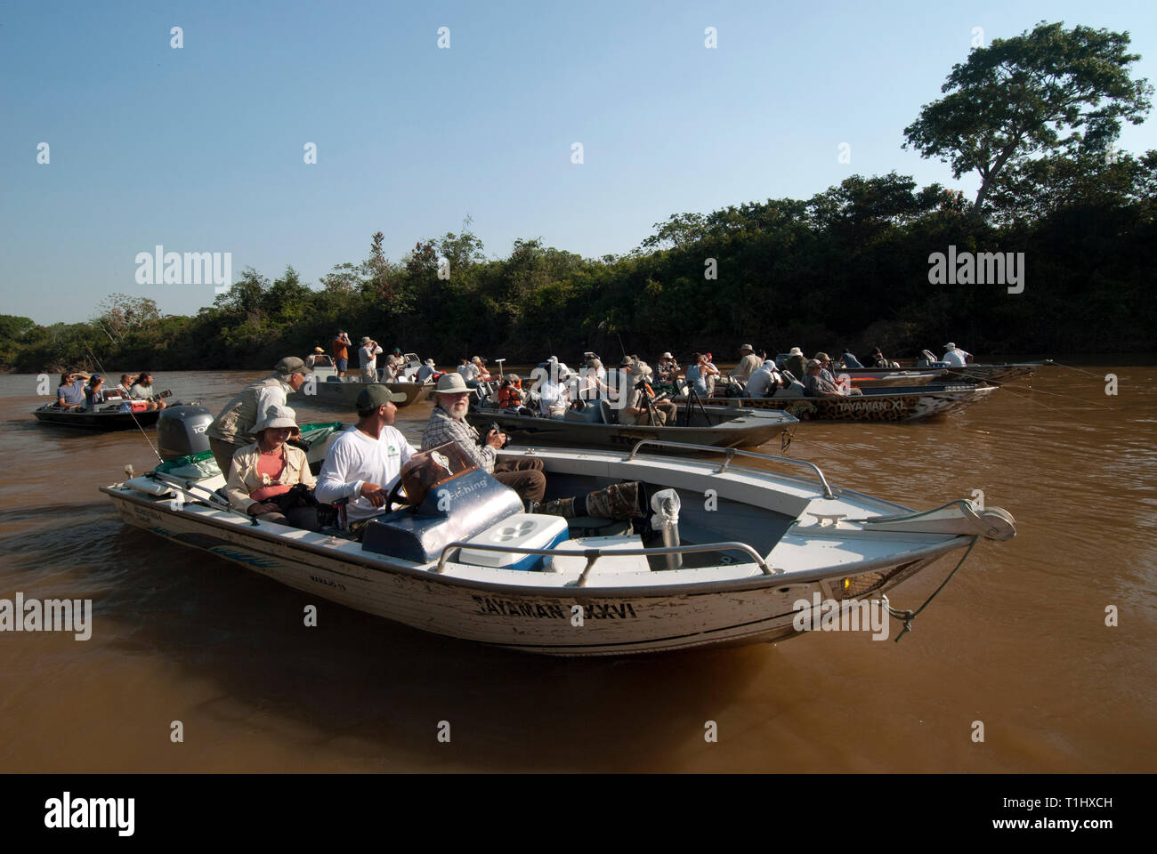 Photographers in boats waiting for a jaguar to wake up in The Pantanal in Brazil Stock Photo
