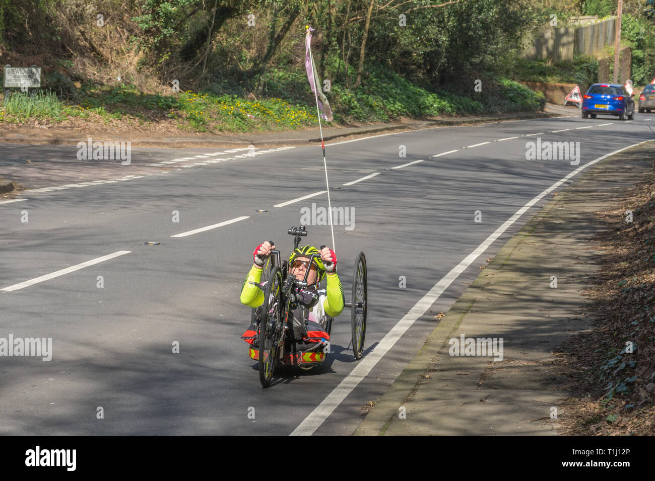 Disabled woman riding a handcycle or handbike on a road in Surrey, UK Stock Photo