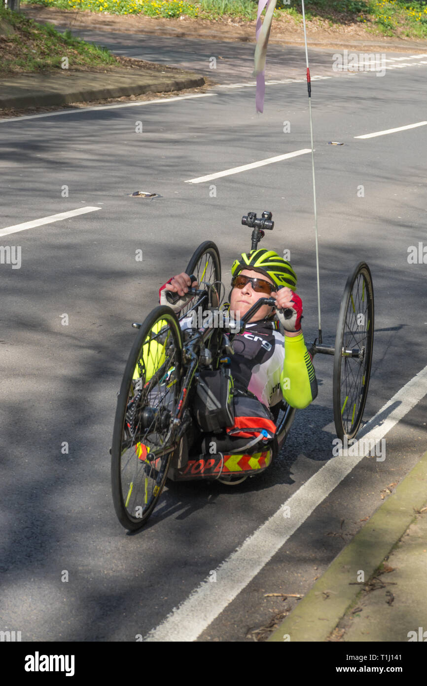 Disabled woman riding a handcycle or handbike on a road in Surrey, UK Stock Photo