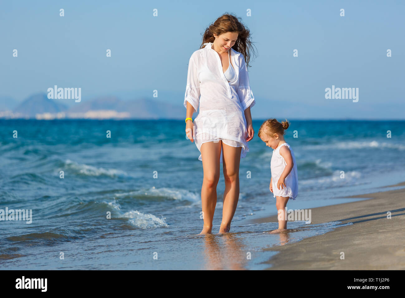 Mother and daughter walking on the beach Stock Photo