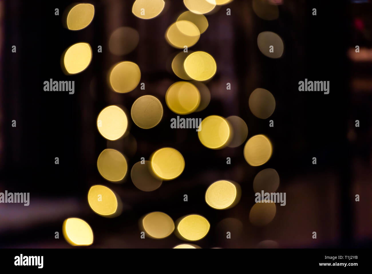 Round bokeh abstract background with yellow golden circles illuminated decoration lights on tree at night evening dark black christmas Stock Photo