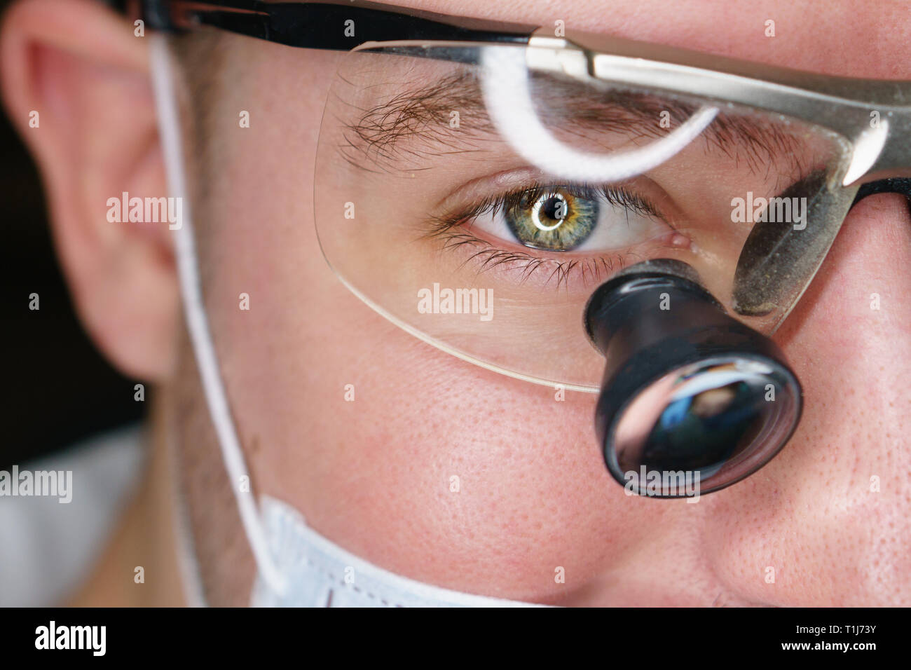 Male dentist in special glasses with magnifying glasses and mask. Medical worker. Stock Photo