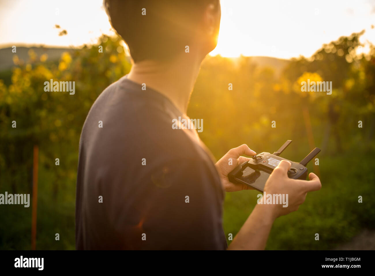 Young man flying a drone in warm evening sunlight Stock Photo