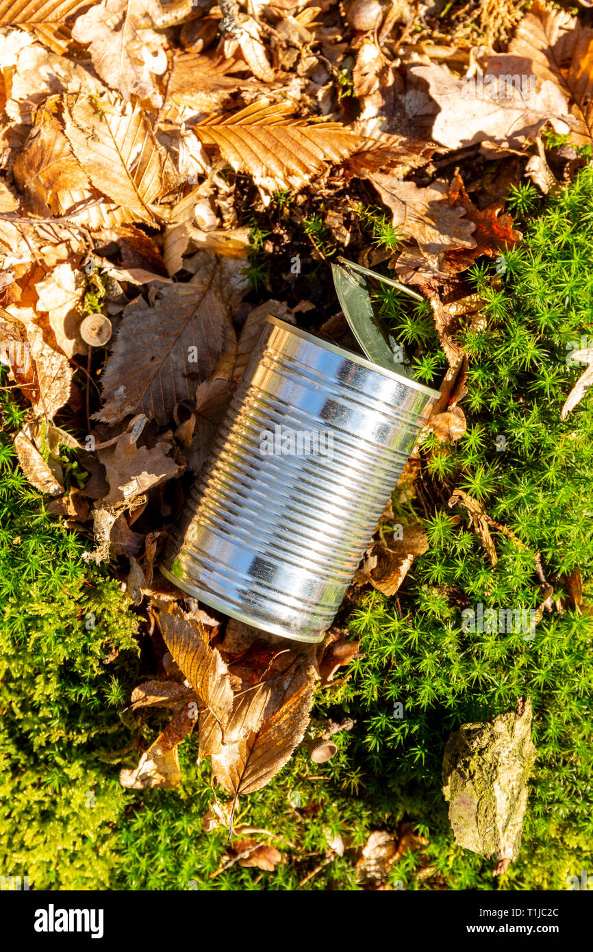 Still life of an empty used tin can with lid and pull waste on forest floor as an environmental pollution closeup Stock Photo