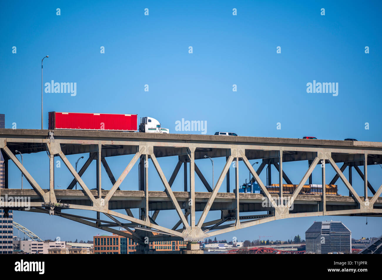 Big rigs Semi Trucks move in opposite directions at different levels of two-tiered overpass bridge with another traffic against the background of high Stock Photo