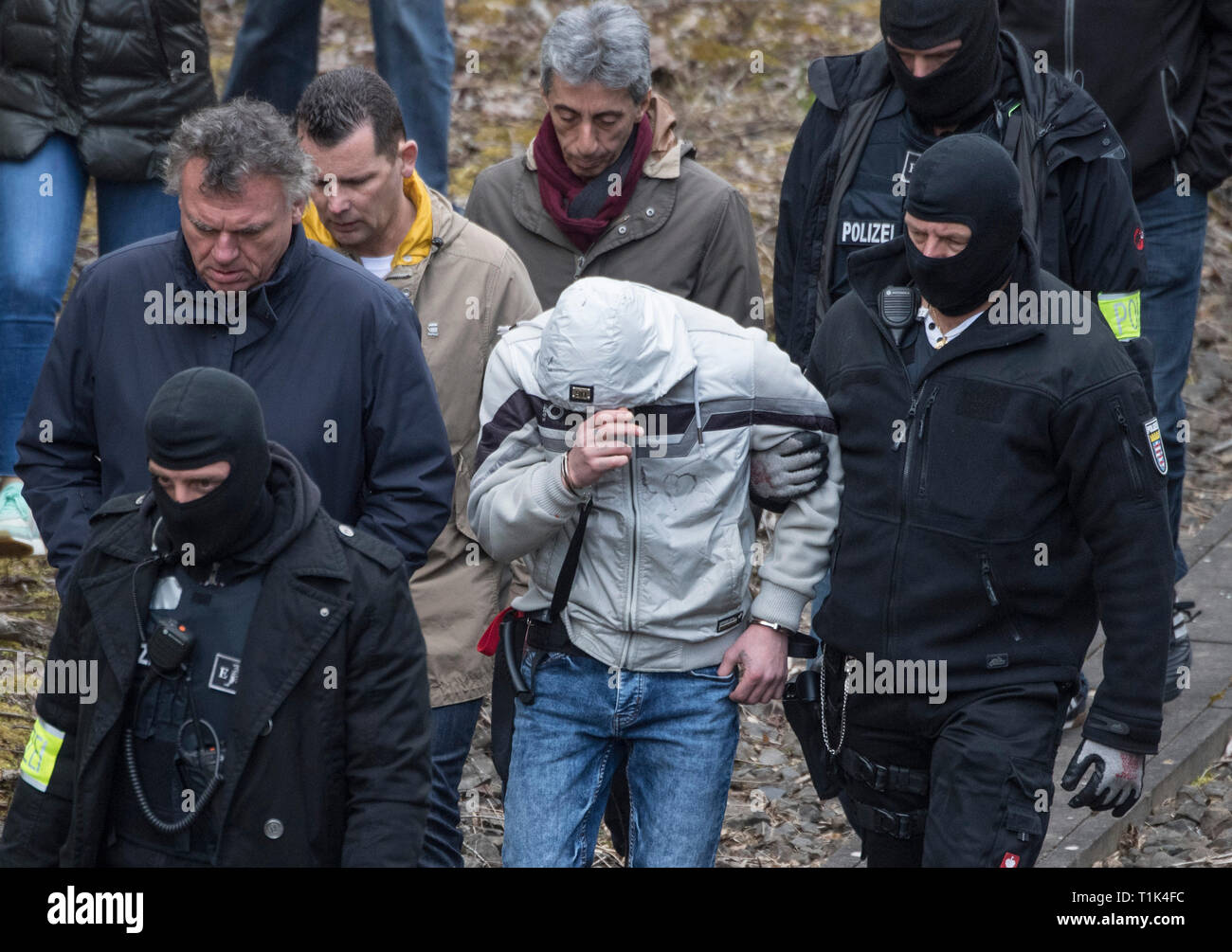 Wiesbaden, Germany. 27th Mar, 2019. Accompanied by two masked police officers, Ali B., accused of murdering 14-year-old Susanna, is led along a railway line near Erbenheim. To the left of him is his defender Marcus Steffel, with whom Kragen gives his second defender Martin Reineke. There's an interpreter behind it. Here the man, who came from Iraq, allegedly raped the girl, then killed her and buried her body. Credit: Boris Roessler/dpa/Alamy Live News Stock Photo