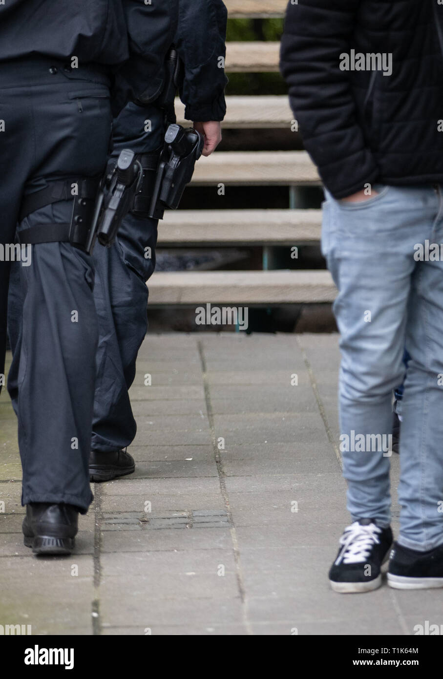 Bielefeld, Germany. 27th Mar, 2019. Policemen carry guns in front of the district court. A trial against eight men on suspicion of a serious breach of the peace begins under great security precautions. The defendants, aged between 20 and 38, are to belong to an extended family. After an argument, one of the men was expelled from a discotheque. The 27-year-old is said to have called his brother and other relatives to it. The argument escalated. Credit: Friso Gentsch/dpa/Alamy Live News Stock Photo