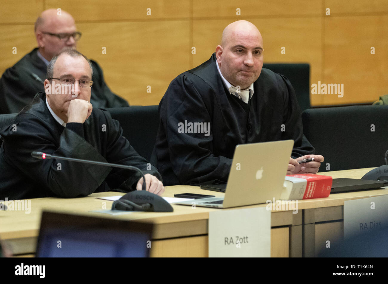 Bielefeld, Germany. 27th Mar, 2019. The defenders of the accused, Andreas Zott (l) and Paulo Dias (r), sit in a hall of the district court. A trial against eight men on suspicion of a serious breach of the peace begins under great security precautions. The defendants, aged between 20 and 38, are to belong to an extended family. After an argument, one of the men was expelled from a discotheque. The 27-year-old is said to have called his brother and other relatives to it. The argument escalated. Credit: Friso Gentsch/dpa/Alamy Live News Stock Photo
