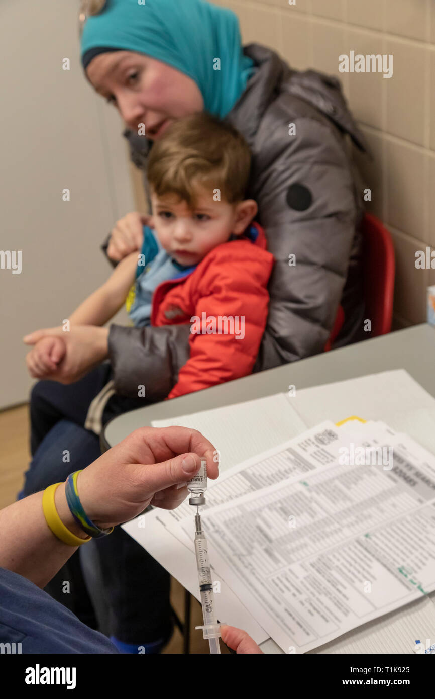 Southfield, Michigan, USA. 27th Mar, 2019. Nurse Jayne DeBoer-Rowse prepares a measles vaccination (MMR) for Adam Almahariq, 2, at the Oakland County Health Department. Twenty-two measles cases have been confirmed in the area since the visit of an infected traveler from Israel. Adam is held by his mom, Miranda Almahariq. Credit: Jim West/Alamy Live News Stock Photo
