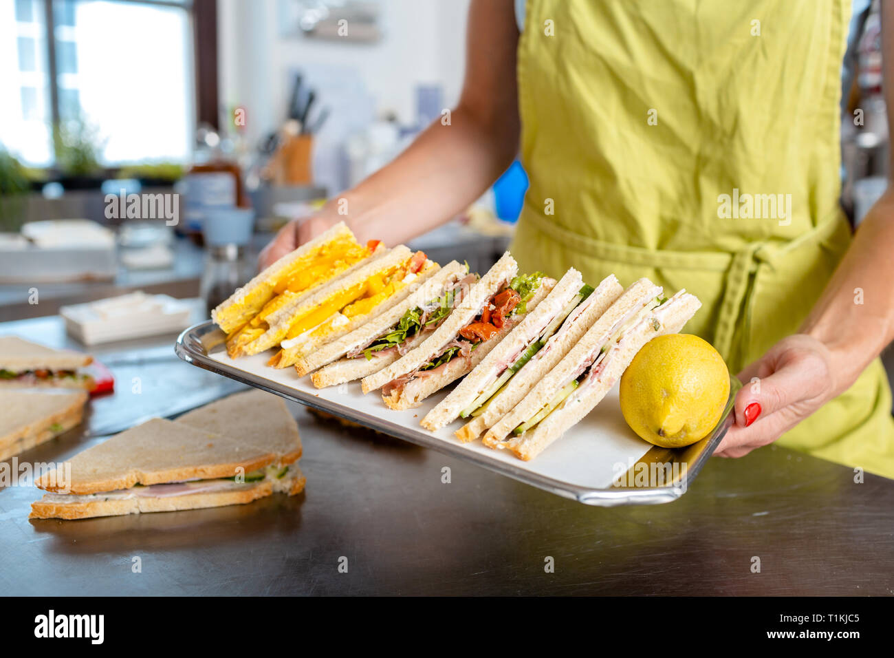 Woman's hand carrying sandwich in tray Stock Photo